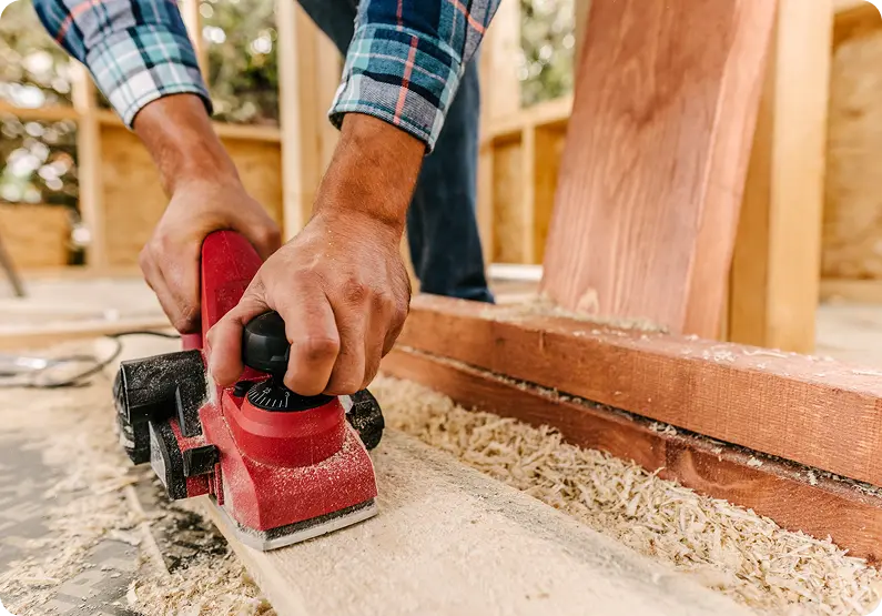 arpintero lijando una superficie de madera con herramienta eléctrica